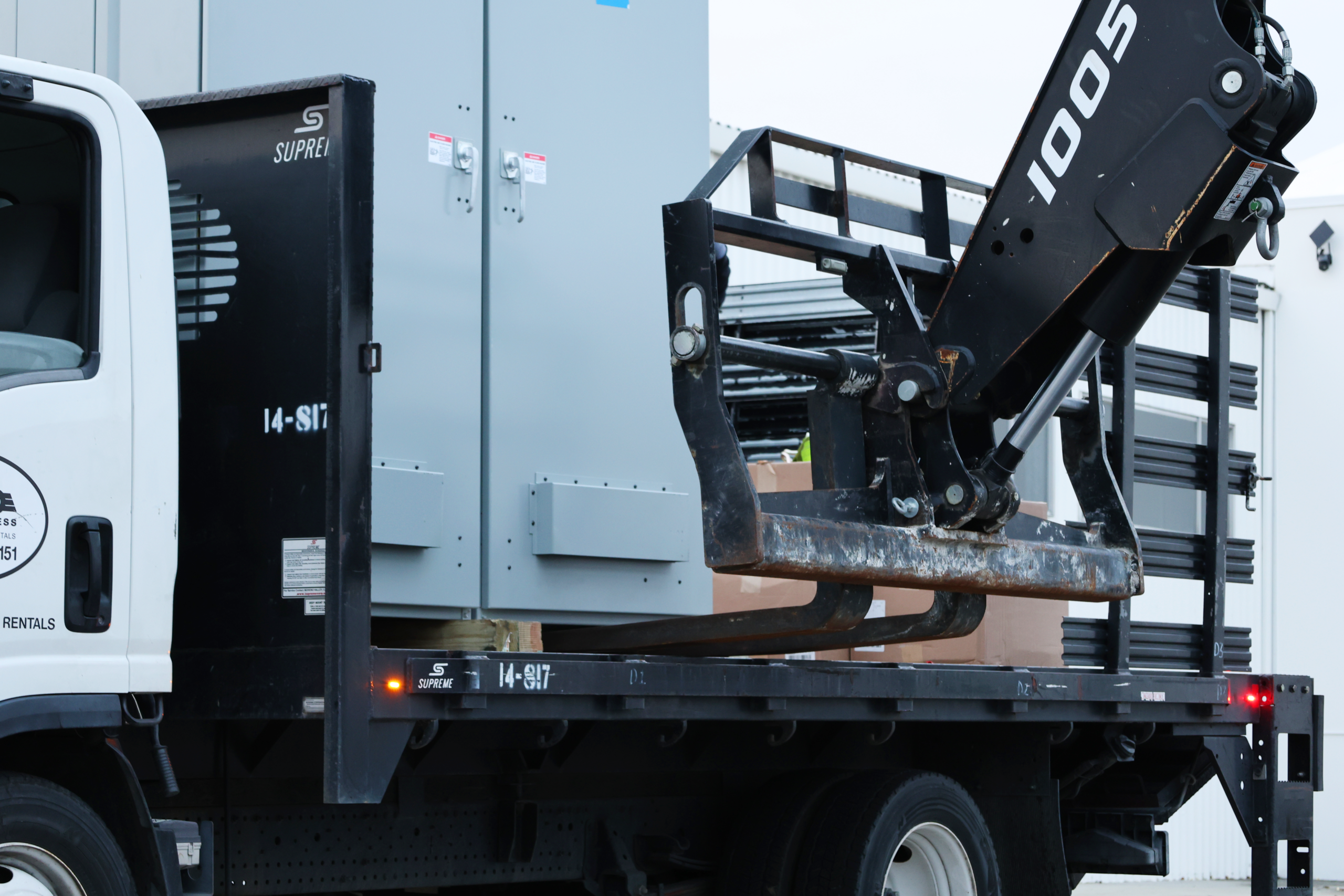 Switchgear Delivery on Boom Truck Gray switchgear enclosure loaded on a flatbed boom truck
