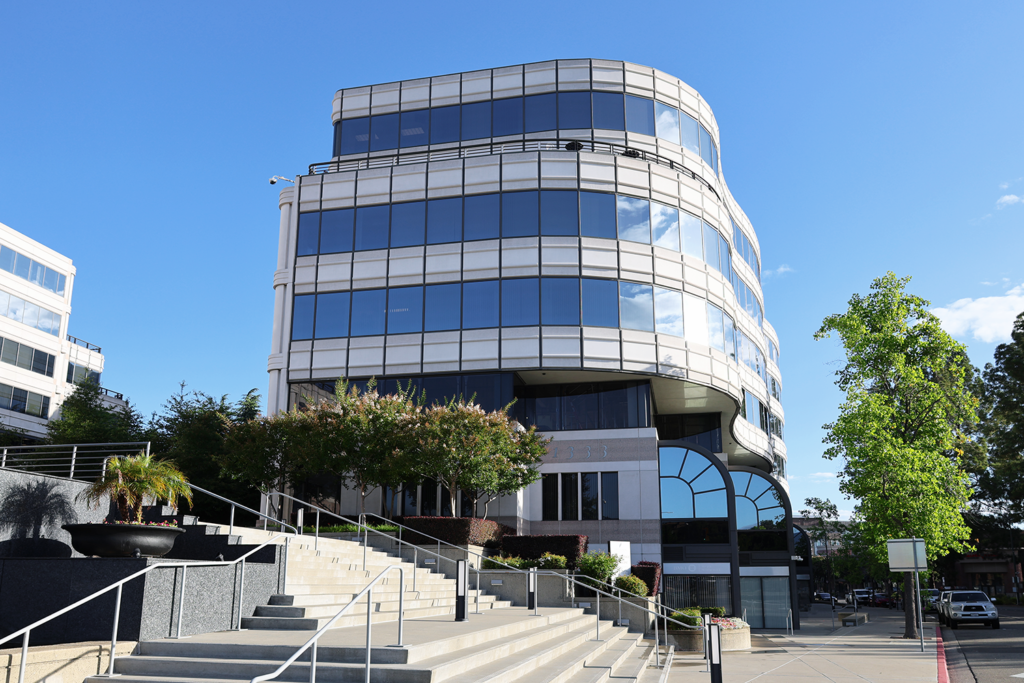 Multi-story glass office building exterior with landscaped entry stairs