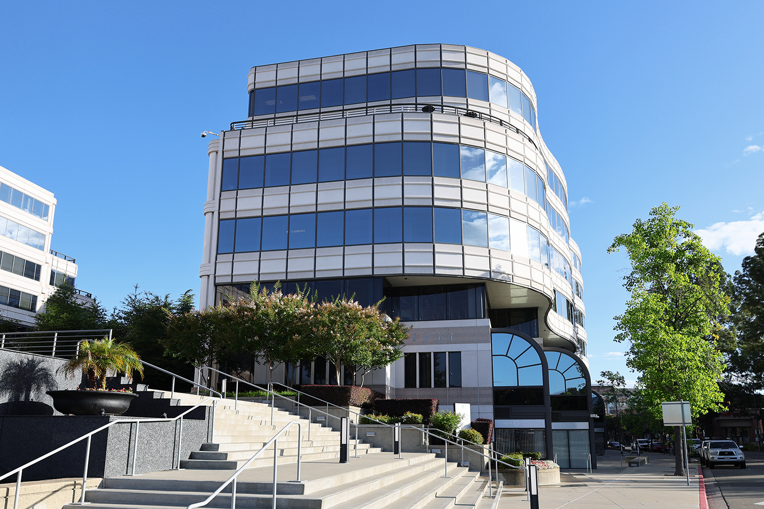Multi-story glass office building exterior with landscaped entry stairs