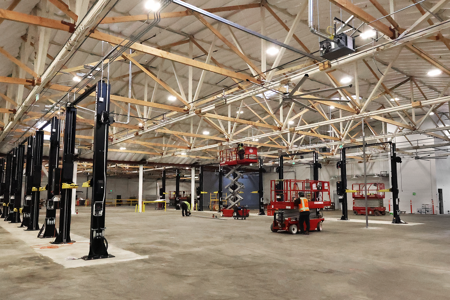Open warehouse interior with high-bay lighting and scissor lifts at the Rivian project